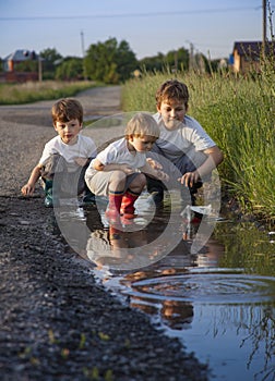 3 boy play in puddle summer day