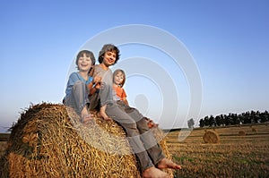 3 boys in a haystack in the field