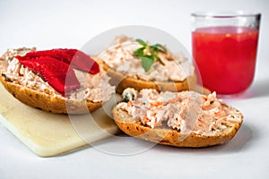 3 canapÃ©s with salmon spread with fresh cheese on board, glass of juice