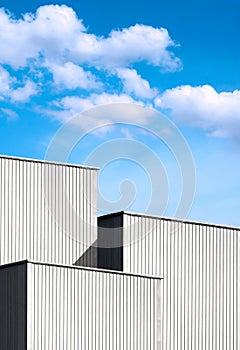 3 Corrugated Metal Industrial Buildings against clouds on blue sky background in vertical frame