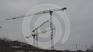3 cranes construction time lapse. Cranes at the construction site are moving construction work. Moving clouds and an