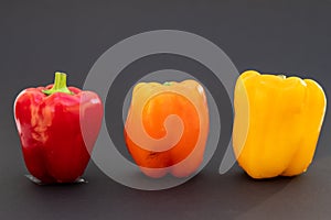 3 different coloured peppers on a dark base, eine rote, eine gelbe und eine orange
