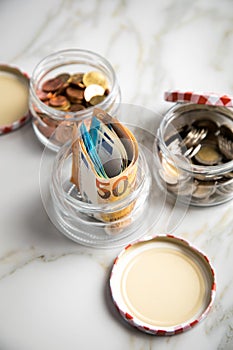 3 glass jars with Euro notes, 2â‚¬ coins and loose cash for housekeeping and savings