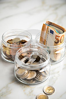 3 glass jars with Euro notes, 2â‚¬ coins and loose cash for housekeeping and savings