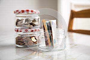 3 glass jars with Euro notes, 2â‚¬ coins and loose cash for housekeeping and savings