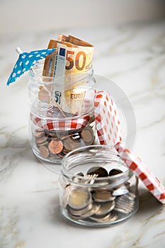 3 glass jars with Euro notes, sunshade, 2â‚¬ coins and loose cash for housekeeping and vacation savings