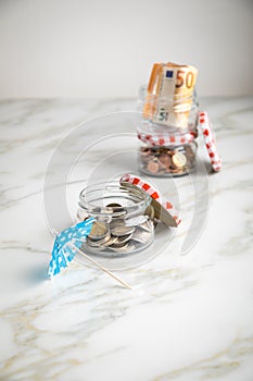 3 glass jars with Euro notes, sunshade, 2â‚¬ coins and loose cash for housekeeping and vacation savings