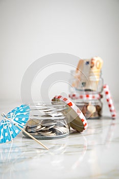 3 glass jars with Euro notes, sunshade, 2â‚¬ coins and loose cash for housekeeping and vacation savings