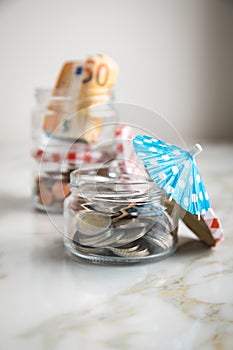 3 glass jars with Euro notes, sunshade, 2â‚¬ coins and loose cash for housekeeping and vacation savings