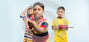 3 indian kids flying kite, one holding spindal or chakri