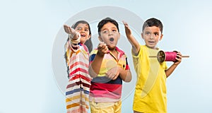 3 indian kids flying kite, one holding spindal or chakri