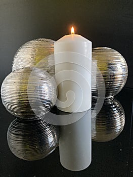 3 metal balls reflected in a glass table with candle