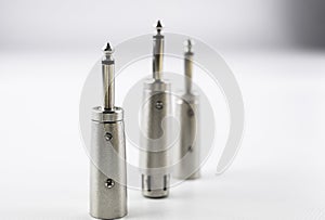 3 mono jack connectors or terminals with conversion to balanced canon type both male and female, all metallic, on white background