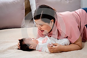 A 3 month old newborn baby is laying in bed happily. and single moms recline for comfort and play. A real mother comforts a