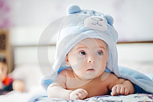 3 months baby boy weared in funny hat lying down on a blanket. A portrait of a cute blond baby