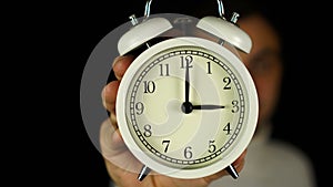 3 o`clock. Human hand holding alarm clock that showing three o`clock and ringing.