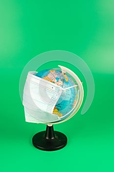 3 ply surgical face mask on world globe isolated on green background