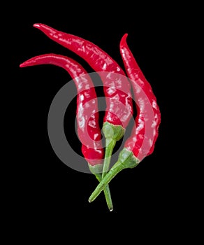3 red chili peppers on black background