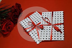 3 red roses with 2 gifts envelopes, red ribbons, certificates, invitation card inside. Craft concept. Red on the red background. C