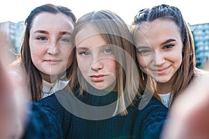 3 teenage girls. They take pictures themselves on phone, happy smiles play have fun. Online application Internet, social