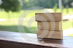 3 Wood Blocks On Wooden polished Table, green nature defocused on the background