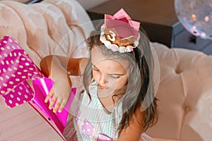 3-year-old birthday girl, unwrapping her birthday present on the couch