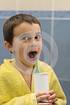 A 3-year-old boy at home washes his teeth with an oral irrigator. Little boy cleaning teeth with oral irrigator. Dental Care