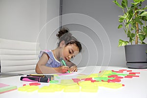 3 year old Latina brunette girl with curly hair draws as therapy for autism and attention deficit hyperactivity disorder ADHD