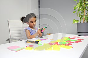 3 year old Latina brunette girl with curly hair draws as therapy for autism and attention deficit hyperactivity disorder ADHD