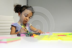 3 year old Latina brunette girl with curly hair draws as therapy for autism and attention deficit hyperactivity disorder ADHD