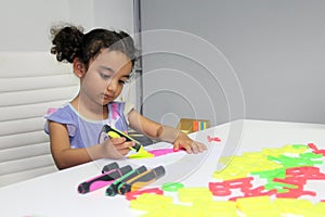 3 year old Latina brunette girl with curly hair draws as therapy for autism and attention deficit hyperactivity disorder ADHD