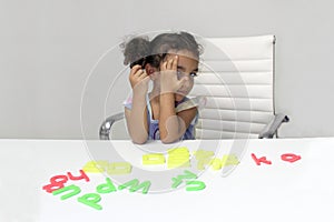 3-year-old Latina girl with brunette and curly hair plays with a game of letters and numbers for learning within the autism