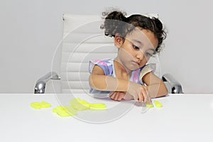 3-year-old Latina girl with brunette and curly hair plays with a game of letters and numbers for learning within the autism