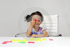 3-year-old Latina girl with brunette and curly hair plays with a game of letters and numbers for learning within the autism