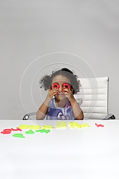 3-year-old Latina girl with brunette and curly hair plays with a game of letters and numbers for learning within the autism