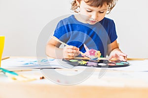 3 years girl painting at the small table at home.