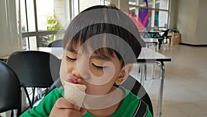 A 3 years old Asian boy enjoys a delicious ice cream cone during the summer. Little kid is eating ice-cream.