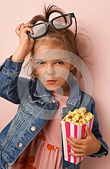 The 3 years old girl with sweet popcorn and cinema glasses