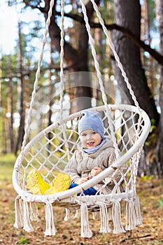 3 years old kid swinging in a hanging chair outdoors