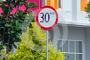 30 km per hour speed limiter city sign on the sidewalk of city commercial area under the morning blue sky