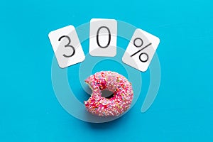 30% off discount - sale concept with bitten donut - on blue background top-down copy space