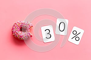 30% off discount - sale concept with bitten donut - on pink background top-down copy space