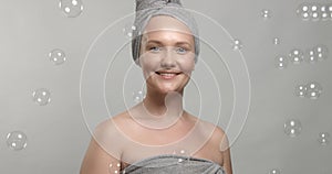 30`s woman wears a towel after bath surrounded by soap bubbles
