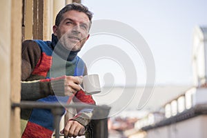 30s or 40s attractive and happy man at home balcony relaxed and cheerful enjoying cup of coffee looking to city street smiling and