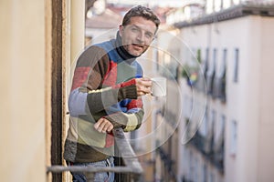 30s or 40s attractive and happy man at home balcony relaxed and cheerful enjoying cup of coffee looking to city street smiling and