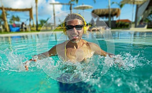 30s cool and relaxed man enjoying playful at tropical luxury resort swimming pool listening to music with headphones feeling