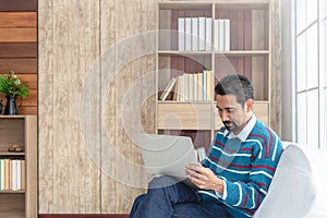 30s handsome businessman  searching and reading article from internet.  Modern arab businessman in casual clothes working at home