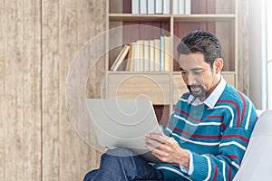 30s handsome businessman  searching and reading article from internet.  Modern arab businessman in casual clothes working at home