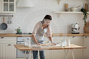 30s woman leaning over table, rolling out dough.