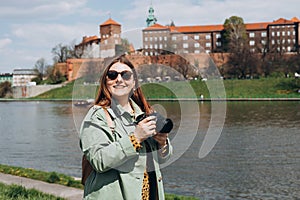 30s woman tourist in stylish clothes making photo at camera the famous Wawel Castle in Krakow. Attractive young female